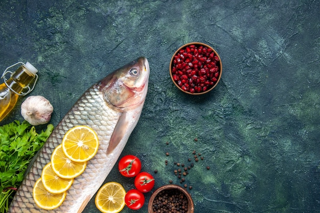 Vista dall'alto pesce crudo pomodori fette di limone sullo spazio libero del tavolo