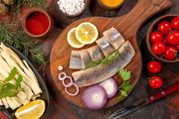 Vista dall'alto pesce fresco a fette con condimenti pomodori e formaggio su sfondo scuro