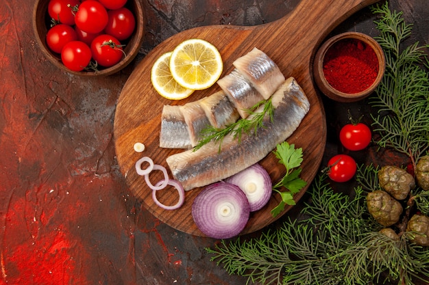 Vista dall'alto pesce fresco a fette con pomodori freschi su sfondo scuro