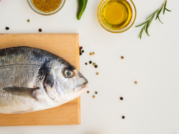 Vista dall'alto pesce fresco con condimenti ed erbe aromatiche