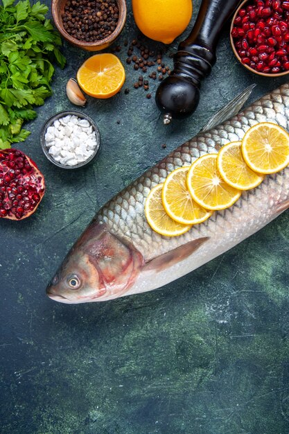 Vista dall'alto pesce fresco con fette di limone macinapepe sul tavolo della cucina