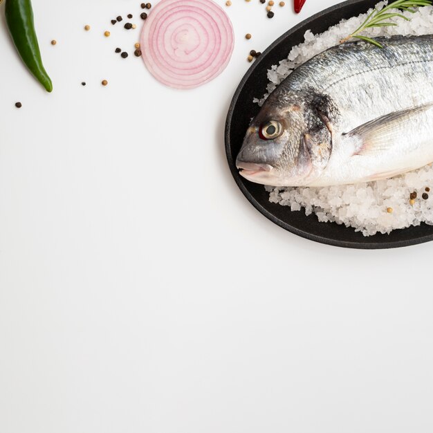 Vista dall'alto pesce fresco sul piatto con condimenti