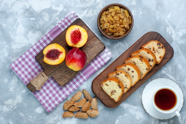 Vista dall'alto pesche fresche frutta dolce e gustosa con torte e uvetta sulla scrivania bianco chiaro