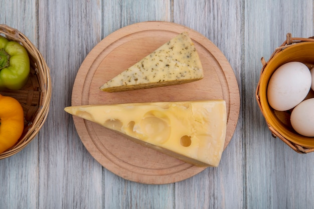 Vista dall'alto pezzi di formaggio olandese su un supporto con peperoni e uova di gallina su uno sfondo grigio