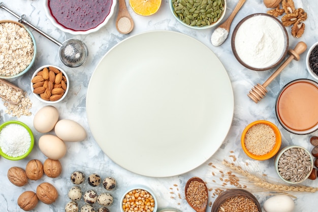 Vista dall'alto piatto bianco ciotole con mandorle semi di mais chicchi di grano semi di sesamo uova noci uova di quaglia