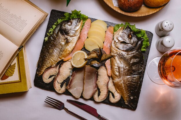 Vista dall'alto piatto di pesce con patate e una fetta di limone con un bicchiere di vino