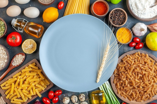 Vista dall'alto piatto grigio tondo con pasta cruda farina verdure condimenti e uova su tavola scura pasta all'uovo cena pasto colore frutta