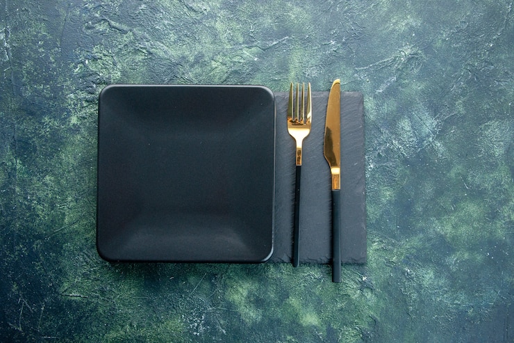 Foto gratuito vista dall'alto piatto quadrato nero con coltello e forchetta d'oro su uno sfondo scuro colore di sfondo cibo ristorante posate cena cucina