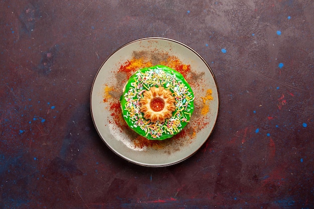 Vista dall'alto piccola deliziosa torta con crema verde sulla superficie scura