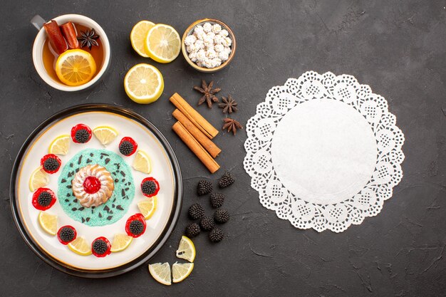 Vista dall'alto piccola deliziosa torta con fette di limone e tazza di tè su sfondo scuro biscotti agli agrumi di frutta biscotto dolce