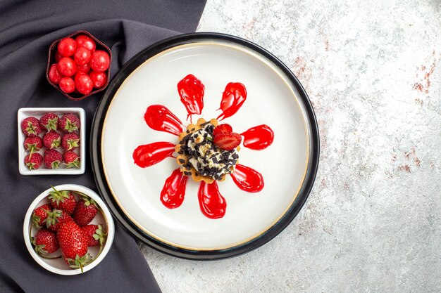 Vista dall'alto piccola deliziosa torta con frutta e caramelle su superficie bianca torta biscotto biscotti torta alla frutta dolce