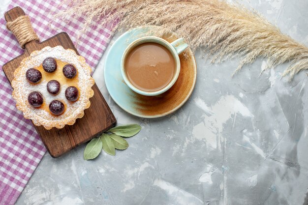 Vista dall'alto piccola torta gustosa con frutta zucchero a velo insieme a caffè al latte su zucchero dolce torta torta biscotto leggera scrivania