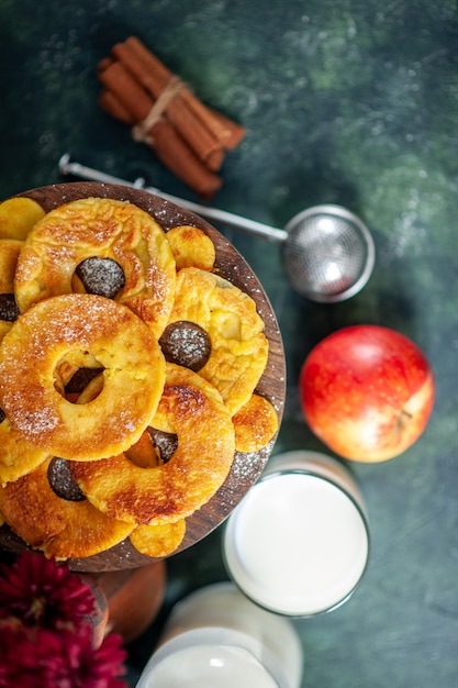 Vista dall'alto piccole deliziose torte a forma di anello di ananas con latte su sfondo scuro hotcake cuocere torta pasticceria colore biscotto torta biscotto alla frutta