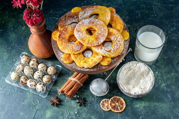 Vista dall'alto piccole deliziose torte a forma di anello di ananas con latte su sfondo scuro hotcake torta al forno biscotto torta di frutta pasticceria