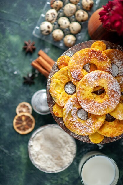 Vista dall'alto piccole deliziose torte a forma di anello di ananas con latte sullo sfondo scuro hotcake torta al forno torta biscotto pasticceria alla frutta