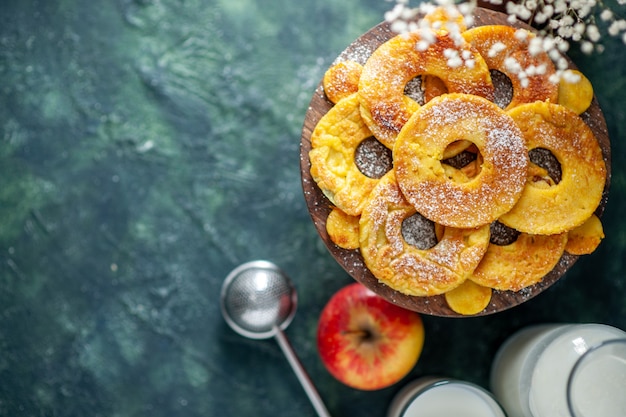 Vista dall'alto piccole torte a forma di anello di ananas con latte su sfondo scuro torta di frutta torta di pasticceria hotcake colore cuocere