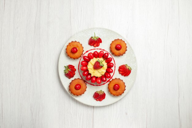 Vista dall'alto piccole torte con frutta all'interno del piatto sulla scrivania bianca