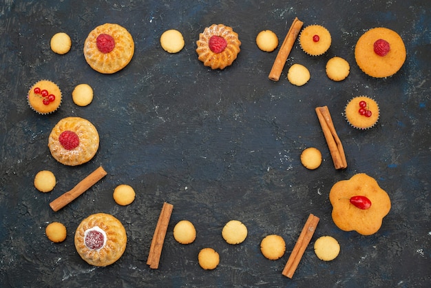 Vista dall'alto piccole torte squisite con crema di biscotti alla cannella sulla scrivania scura dolce biscotto torta dessert frutta bacca