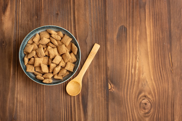 Vista dall'alto piccoli biscotti cuscino all'interno del piatto sulla scrivania marrone