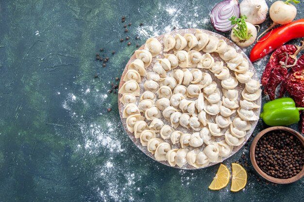 Vista dall'alto piccoli gnocchi crudi con farina e verdure su sfondo scuro pasta di carne piatto alimentare calorie colore cuocere farina di verdure