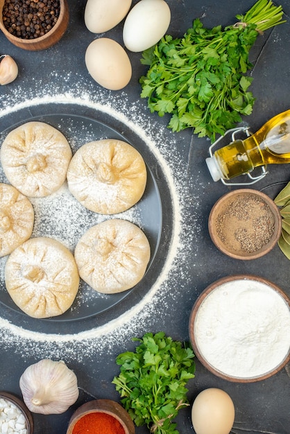 Vista dall'alto piccoli gnocchi crudi con ingredienti diversi sullo sfondo grigio torta di cibo cucinare una gustosa pasta di carne color farina cuocere