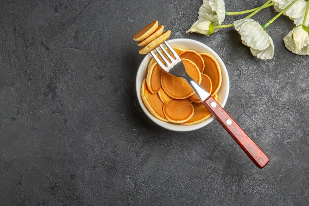 Vista dall'alto piccoli pancake con fiori bianchi sul grigio