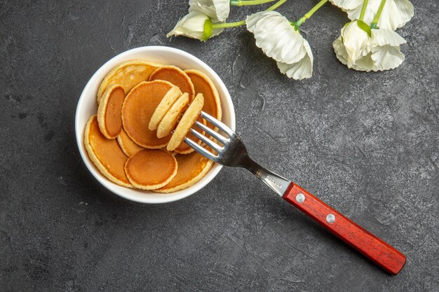 Vista dall'alto piccoli pancake con fiori bianchi sul grigio