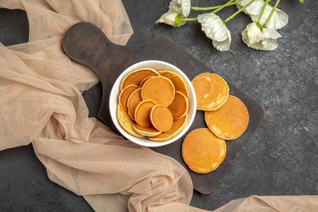 Vista dall'alto piccoli pancake con fiori bianchi sul grigio