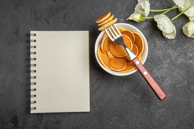 Vista dall'alto piccoli pancake con fiori bianchi sul grigio