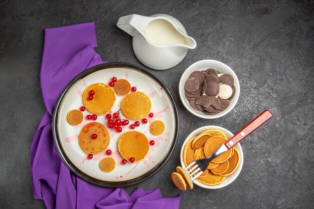 Vista dall'alto piccoli pancake con una tazza di tè e biscotti al buio