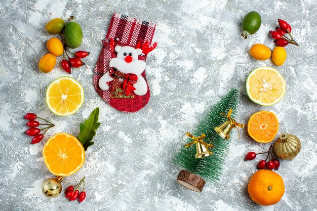 Vista dall'alto piccolo albero di natale calza di natale feijoas tagliati limoni sul tavolo grigio