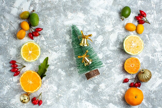 Vista dall'alto piccolo albero di natale tagliato limoni rosa canina sul tavolo grigio