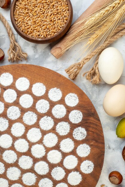 Vista dall'alto piccolo impasto rotondo intorno alle uova gelatina di farina e pane scuro su sfondo bianco cuocere la torta di colore della torta all'uovo forno hotcake al latte