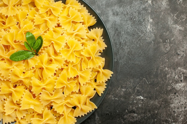 Vista dall'alto poca pasta cruda all'interno del piatto su sfondo grigio scuro