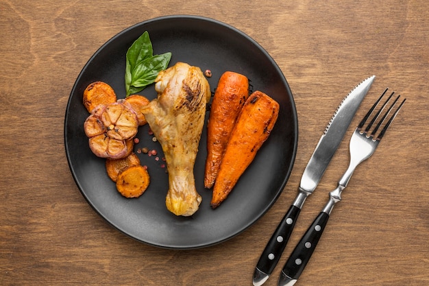 Vista dall'alto pollo al forno e verdure sul piatto con posate