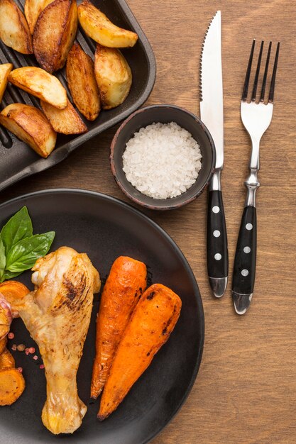 Vista dall'alto pollo al forno e verdure sulla piastra con spicchi e sale