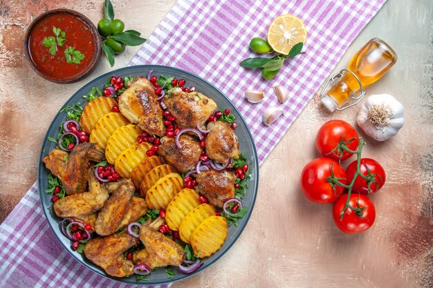 Vista dall'alto pollo ali di pollo patate limone olio sulla tovaglia aglio pomodori