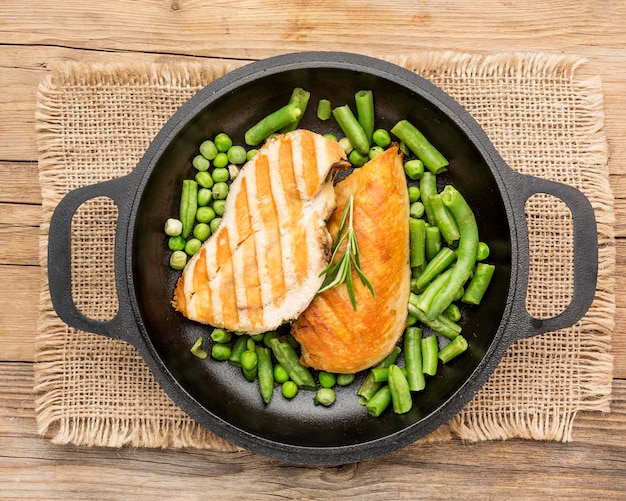 Vista dall'alto pollo alla griglia e piselli in padella con erbe aromatiche