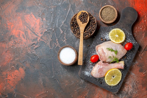 Vista dall'alto pollo crudo fresco con limone su sfondo scuro cucina cibo colore pasto salsa cena piatto di carne