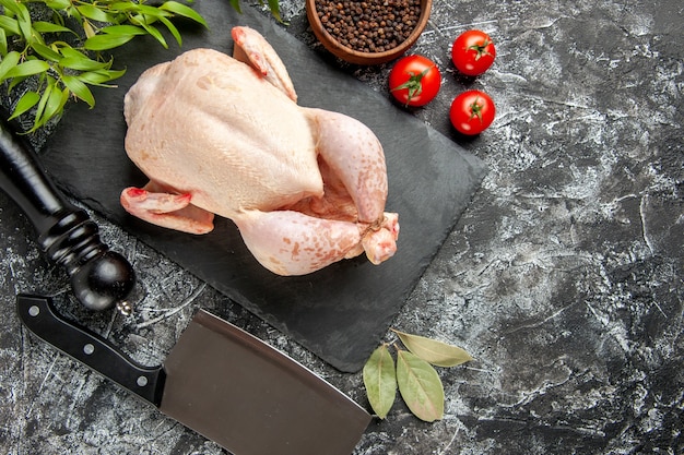 Vista dall'alto pollo crudo fresco con pomodori su sfondo chiaro-scuro pasto da cucina foto animale carne di pollo colore fattoria