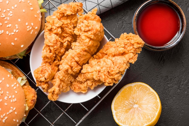 Vista dall'alto pollo fritto e hamburger sul vassoio con salsa e limone