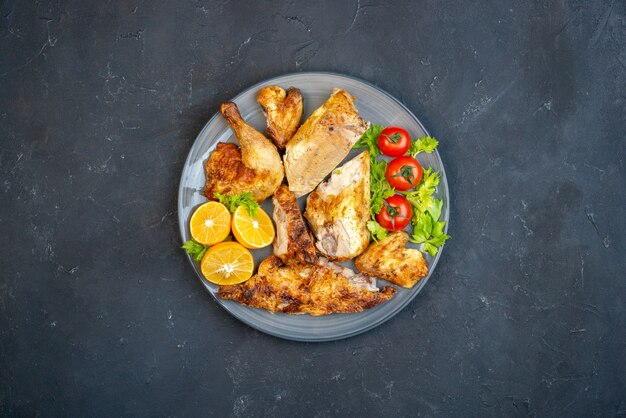 Vista dall'alto pollo fritto pomodori fette di limone in piatto ovale sullo spazio libero del tavolo