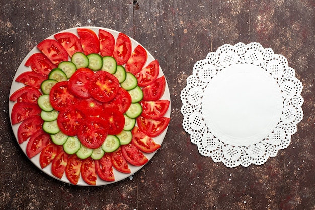 Vista dall'alto pomodori rossi freschi affettati insalata fresca sullo spazio marrone