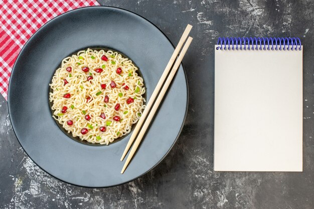 Vista dall'alto ramen noodles chopstics su piatto rotondo scuro