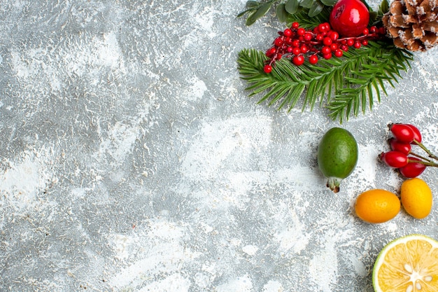 Vista dall'alto rami di alberi di Natale tagliati limoni feijoas sul tavolo grigio con posto per la copia