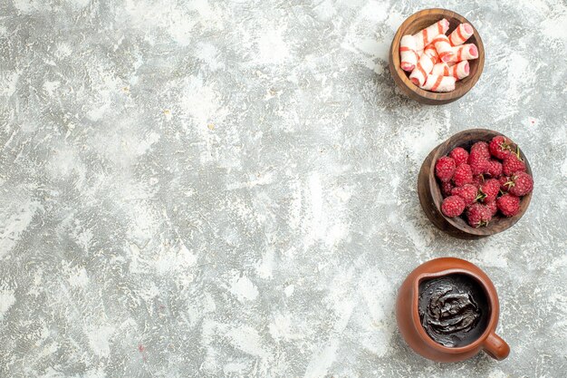 Vista dall'alto ravvicinata di una brocca di cioccolato, una ciotola di lamponi e una ciotola di biscotti su uno sfondo di marmo