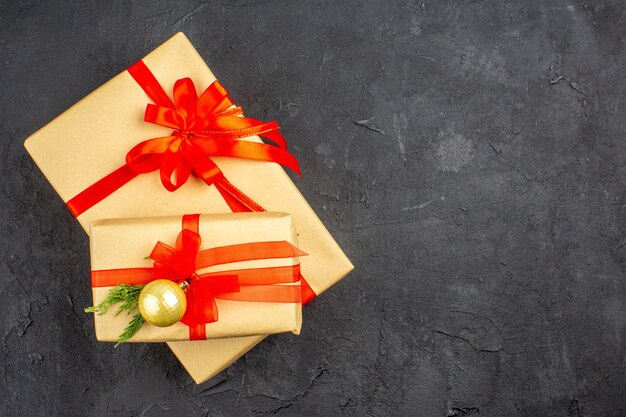 Vista dall'alto regali di Natale grandi e piccoli in carta marrone legati con nastro rosso su superficie scura