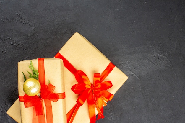 Vista dall'alto regali di Natale grandi e piccoli in carta marrone legati con una palla di nastro rosso su una superficie scura