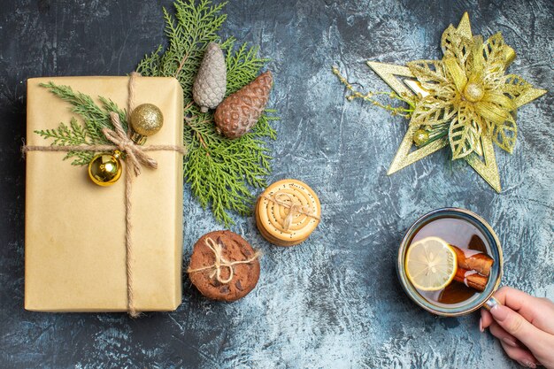 Vista dall'alto regalo di Natale con biscotti dolci e tazza di tè sullo sfondo chiaro-scuro