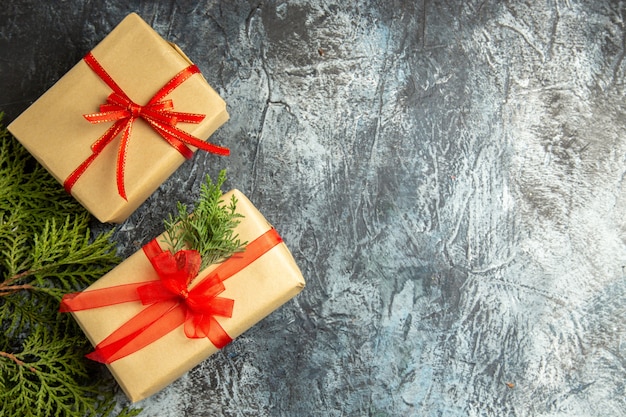 Vista dall'alto regalo di natale piccoli regali rami di pino su sfondo grigio con spazio libero